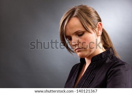 Portrait of a sad business woman looking down against gray background