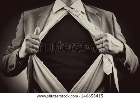 Conceptual image of a man tearing off his shirt over gray background