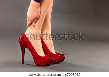 Closeup Of Woman Holding Her Injured Ankle Over Gray Background