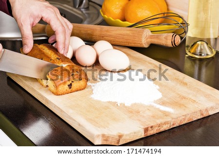 Man cutting a cake on  wooden chopping board in the kitchen