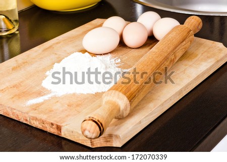 Flour  with eggs and rolling pin on  wooden  board
