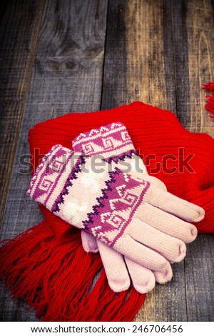 Closeup of knitted winter gloves and scarf on wooden board