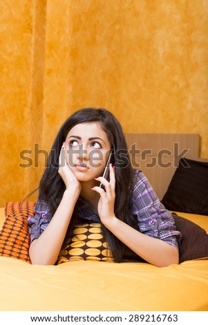 Closeup of  beautiful teenage girl speaking on  smart phone on the bed in her bedroom