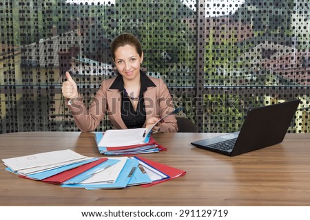 Portrait of young businesswoman with thumb up working at desk  in her office