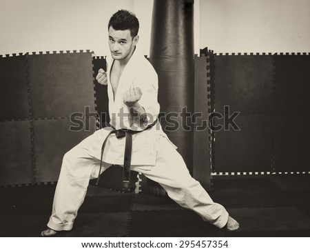 Full length portrait of young man in kimono training ashihara martial art  at the gym