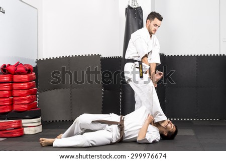 Two young men in kimono fighting during their training  in the gym