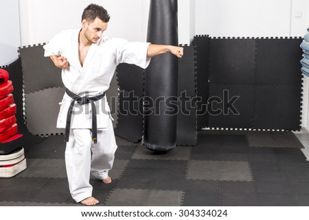 Full length portrait of young man in kimono training ashihara martial art in the gym