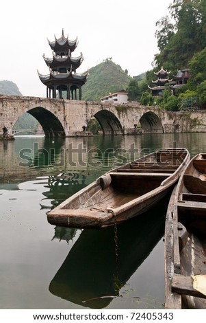 old chinese river boat with bridge and pagoda in the background