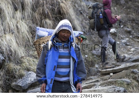 KATHMANDU, NEPAL - April 15,:Mountain porter carrying heavy load in Himalayas, Nepal. April 15, 2015 in Kathmandu, Nepal