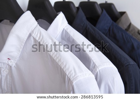 row of white and grey shirts hanging on coat hanger in white wardrobe