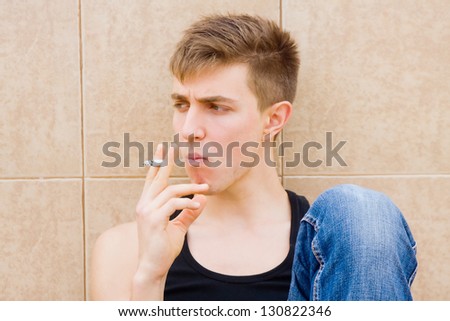 Young man with troubled look smoking off camera