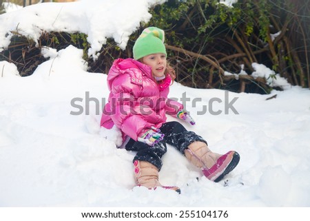 Cute blonde little girl sitting in the snow in her backyard in Jerusalem with tired expression