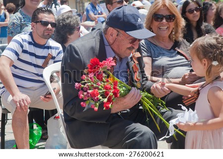 TEL AVIV - May 08: World War II veteran talks to little girl who brings him flowers during celebration of WWII Victory Day on May 08, 2015