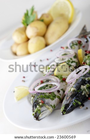 grilled fish with garlic and pepper served with potatoes and lemons