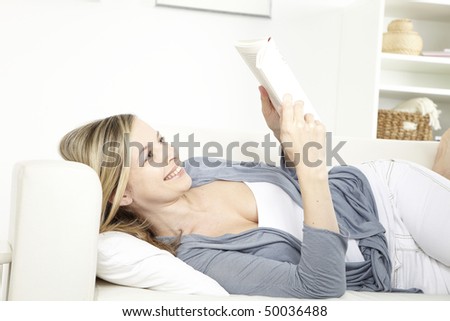 young woman sits on sofa and reads one book