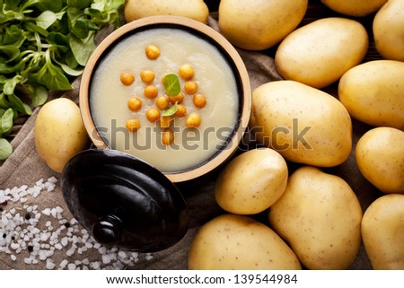 Traditional homemade potatoes cream soup served in vintage ceramic bowl. Dish and fresh ingredients composition.