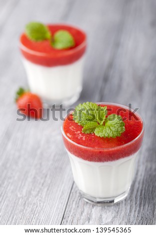 Sweet strawberry mousse with organic yoghurt served in panna cotta way. Fresh fruit dessert decorated with melissa leaf.