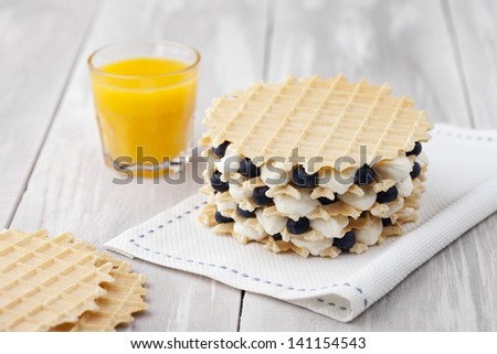 Traditional homemade fresh baked waffles served with blueberries and whipped cream. Dessert and fresh ingredients composition.