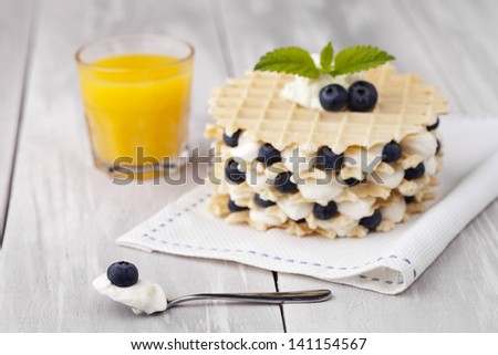 Traditional homemade fresh baked waffles served with blueberries and whipped cream. Dessert and fresh ingredients composition.