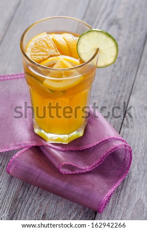 Hot citrus flavor tea served with orange and lemon slices. Full of spices winter time drink on violet tablecloth.