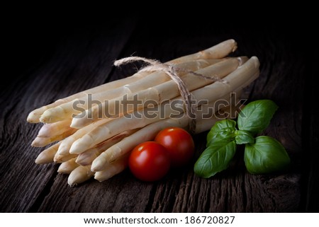 Fresh white asparagus bunch, tomatoes and basil composition. Spring vegetables tied with a string taken on white background.