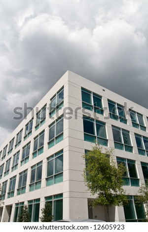 Modern office building in office park with gloomy looming clouds