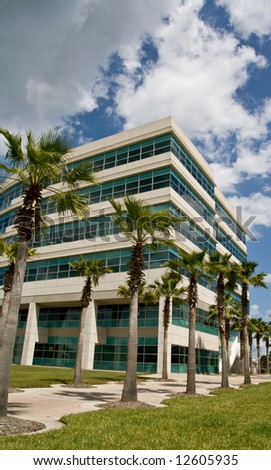 Modern office building in office park with trees and partly cloudy afternoon sky