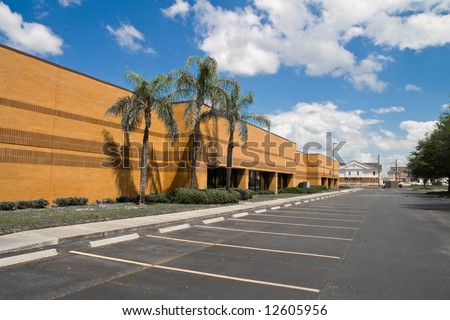 Side of office building with parking spaces and palm trees