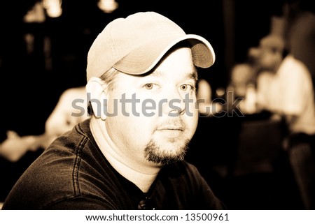 Portrait of a man in a hat in a crowded restaurant or bar