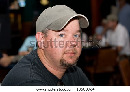 Portrait of a man in a hat in a crowded restaurant or bar