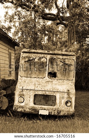 Sepia toned courier or maybe ice cream truck abandoned and covered in moss and lichens