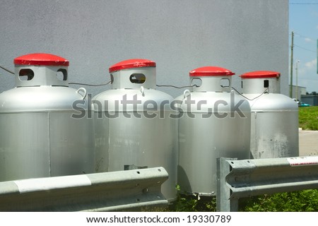 Four large propane tanks in a row up against a wall