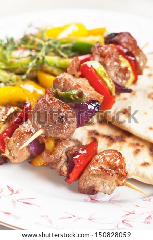 Grilled meat and vegetable kebab on skewer with pita bread