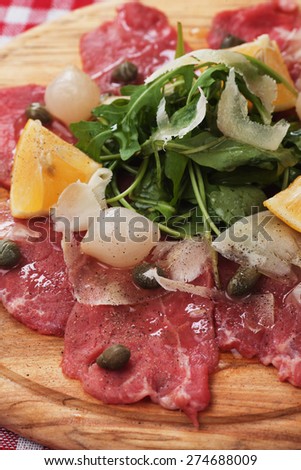 Beef carpaccio with capers, lemon, rocket salad and parmesan cheese