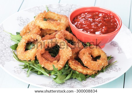 Deep fried battered onion rings with rocket salad and salsa dip