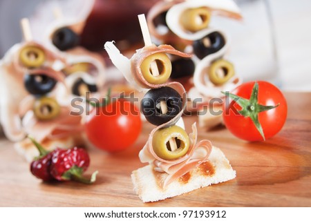 Delicious canape with toasted bread, prosciutto and pickled olive