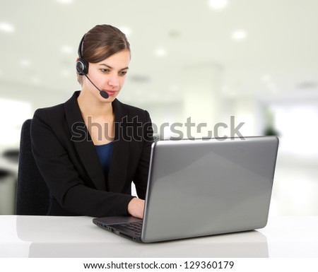 Attractive business woman with headset working on a laptop computer in an office environment