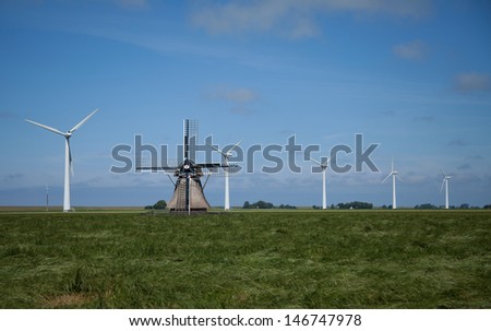 Traditional dutch windmill with modern wind turbines in the background. Old vs new