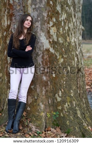 Girl leaning against a tree