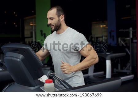 Muscular man running on a treadmill in a fitness club, sport in the fitness club