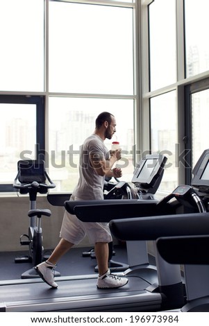 muscular man running on a treadmill in a fitness club, sport in the fitness club