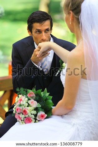 Young groom gives kiss for hand