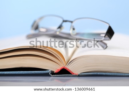 Open book on blue with eyeglasses