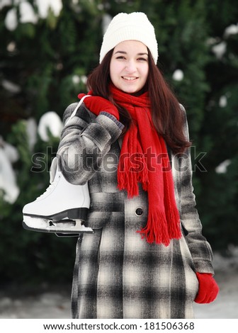 Beautiful young woman holding ice skate in her hand over shoulder outdoors