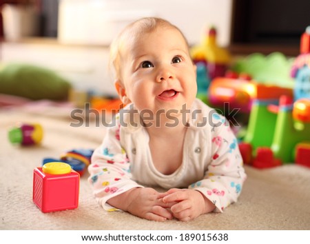 Cute smiling baby lying on floor among toys