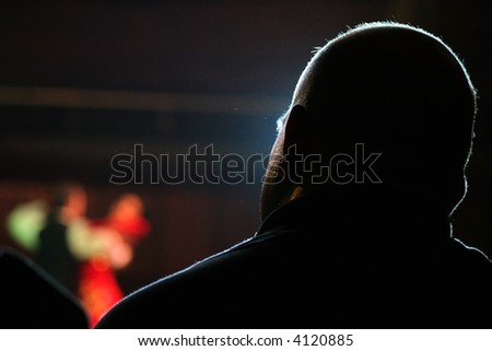 Bald men is watching a dancer of couple in the background