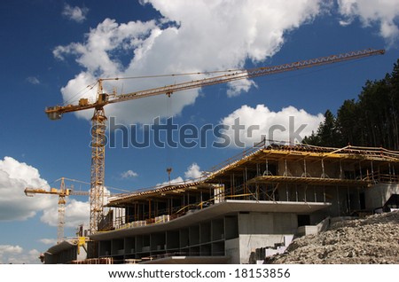 Concrete building built with tower crane at nice cloudy sky