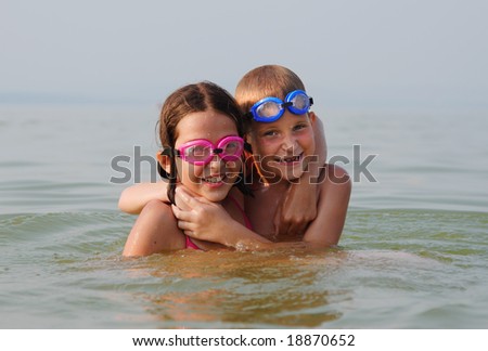 Happy brother and sister embrace each other in the water
