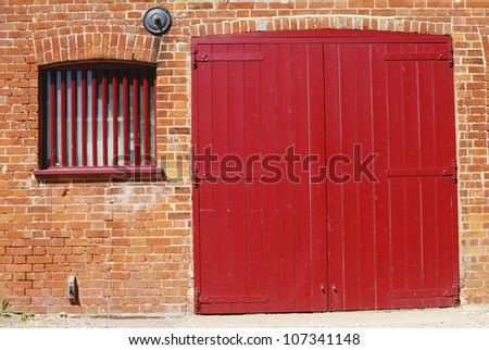 Red double door and barred window in brick wall at Dell Quay. Chichester Harbor. West Sussex. England
