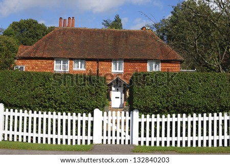 Tiled and brick cottage behind picket fence at Chiddingfold. Surrey. England